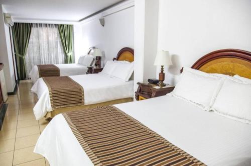 a hotel room with two beds with white sheets at Hotel Casa Laureles in Medellín