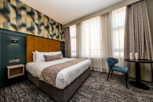 a hotel room with a bed and a table and window at The Maiden City Hotel in Derry Londonderry