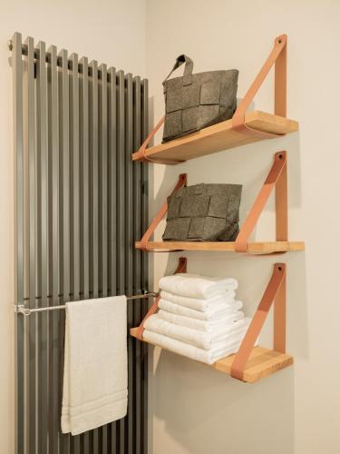 a towel rack with wooden shelves next to a radiator at OSTKÜSTE - Villa Groth Design Apartments in Heringsdorf