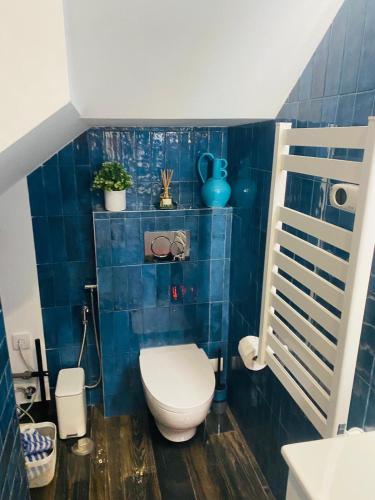 a bathroom with a toilet and a blue tiled wall at Confort à Loulé in Loulé