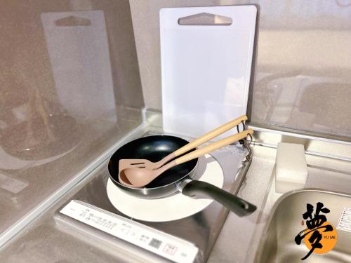 a pan on a stove with wooden utensils in it at Yume夢 堺店 in Sakai