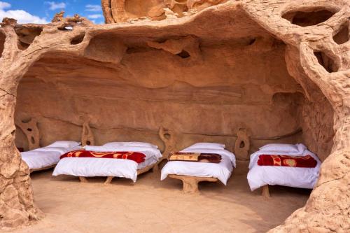 a group of four beds in a cave at Wadi Rum Cave Camping in Wadi Rum