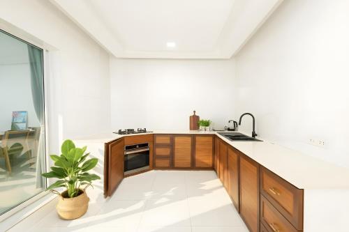a kitchen with white walls and wooden cabinets and a plant at Spacious 3BR BKK NEAR 3 Private Bathrooms FAMILY STAY in Min Buri