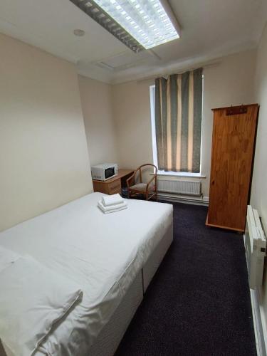a bedroom with a large white bed and a window at Ilford York Hotel in Ilford