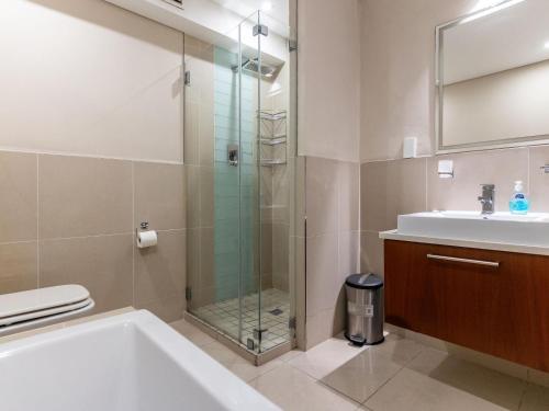 a bathroom with a shower and a tub and a sink at 167 Eden on the Bay in Big Bay
