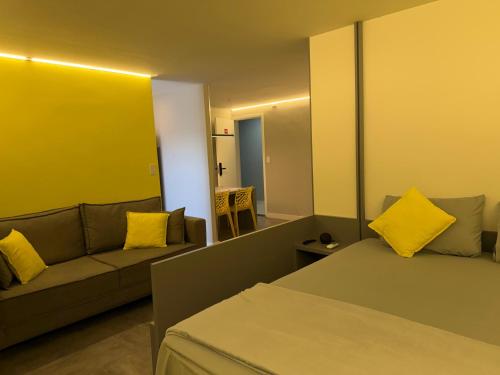 a room with a bed and a couch and a mirror at Flat Red Sorocaba - Yellow in Sorocaba