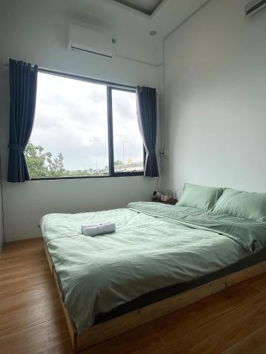 a bed in a room with a large window at Lunara Homestay in Phú Vang