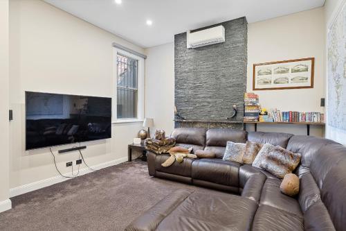 a living room with a leather couch and a large tv at Huge, Inner Sydney City 5 Bed Mansion, Near Opera House - 7 mins in Sydney