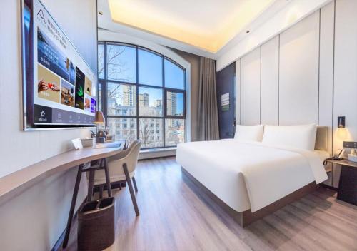 a hotel room with a bed and a desk and a tv at Atour X Hotel Shenyang Beiling Park in Shenyang