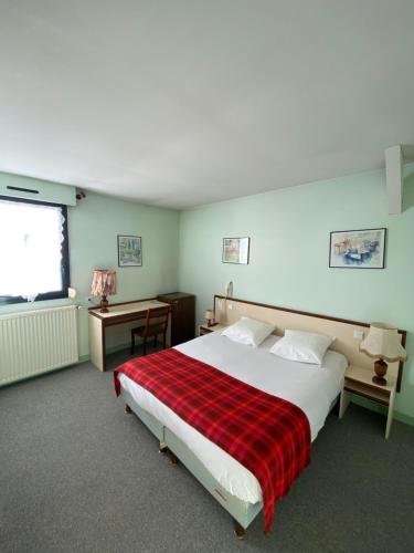 a bedroom with a large bed with a red plaid blanket at Le Grand Connétable in Châteauneuf-de-Randon