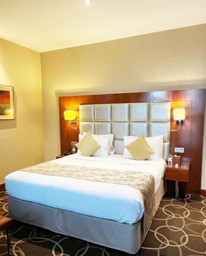 a large bed in a hotel room with two lamps at Montreal Barsha Hotel in Dubai