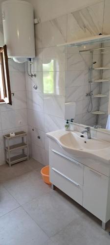 a white bathroom with a sink and a mirror at Apartments Stanko in Sumartin