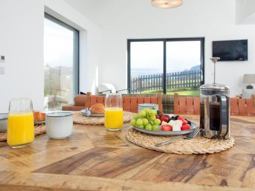 two glasses of orange juice and a plate of fruit on a table at Faodail in Portree