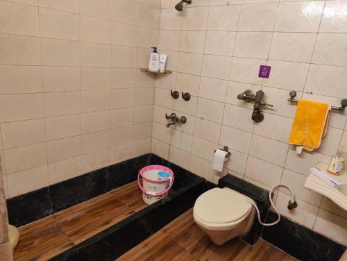 a bathroom with a toilet and a sink with a bucket at Shri Rang Ji Palace in Vrindāvan