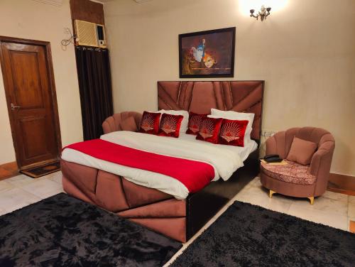 a bedroom with a large bed and two chairs at Shri Rang Ji Palace in Vrindāvan