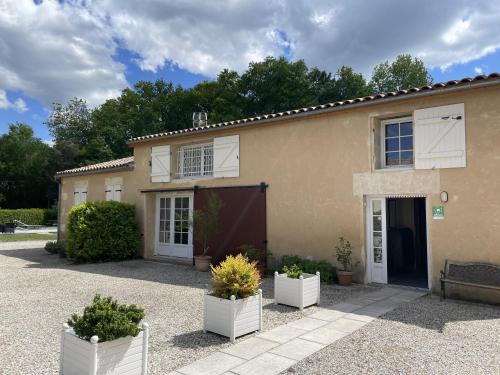 a house with three potted plants in front of it at Les Gîtes du Domaine de Ludeye in Listrac-Médoc