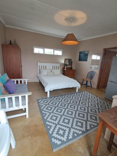 a bedroom with two beds and a blue rug at Haus Windhoek - Charming Coastal Escape in Struisbaai