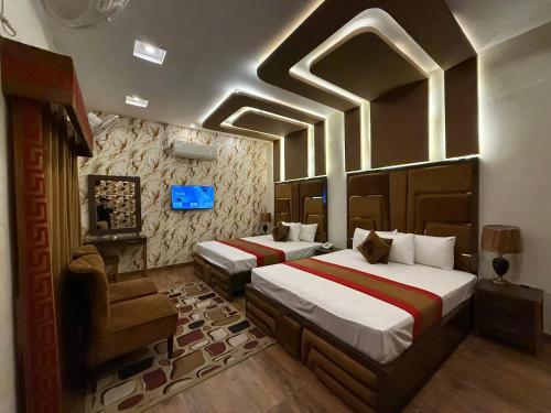 a bedroom with two beds and a chair at Gulberg Inn Hotel Lahore in Lahore