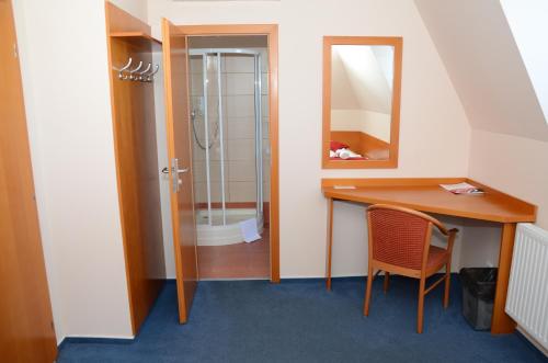 a bathroom with a shower and a desk and a mirror at Hotel Rudolf in Havířov