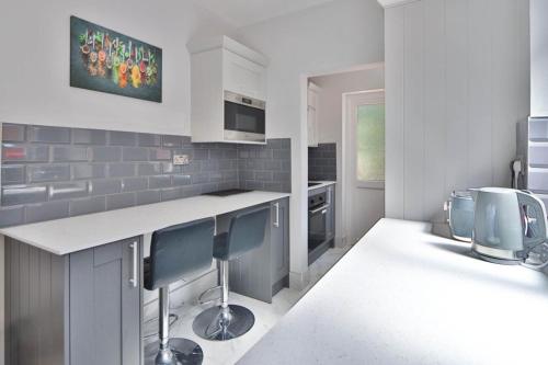 a kitchen with a counter and some blue chairs at Surbiton Home with free parkings, Surbiton, Kingston upon Thames, Surrey, Greater London UK in Surbiton