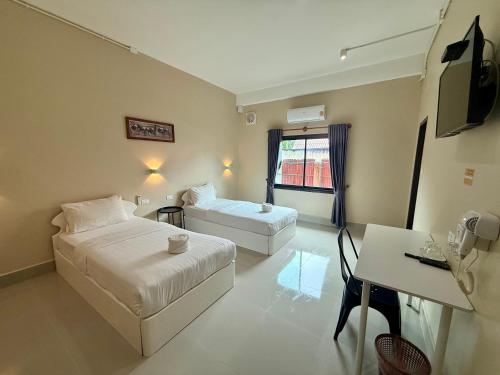 una camera d'albergo con due letti e una scrivania di Phaythavone Hotel a Pakse