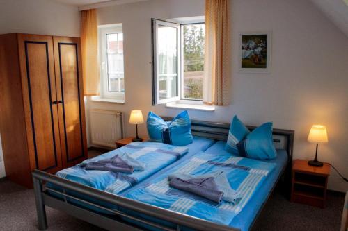 a bedroom with a bed with blue sheets and pillows at Landhaus Behrenwalde in Weitenhagen