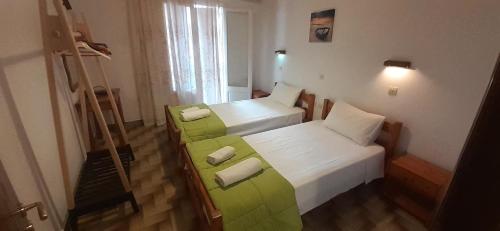 a bedroom with two beds and a green couch at Apartments Elena in Kavos