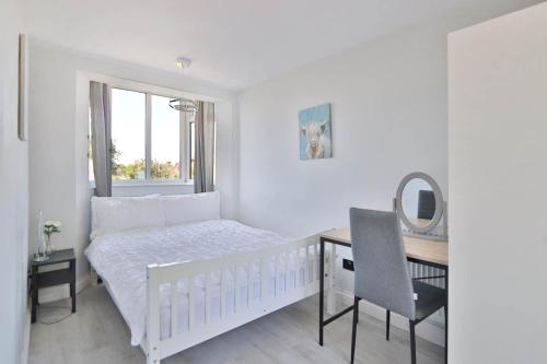 a white bedroom with a bed and a desk with a mirror at Highfield Home with free parkings, Surbiton, Kingston upon Thames, Surrey, Greater London , UK in Surbiton