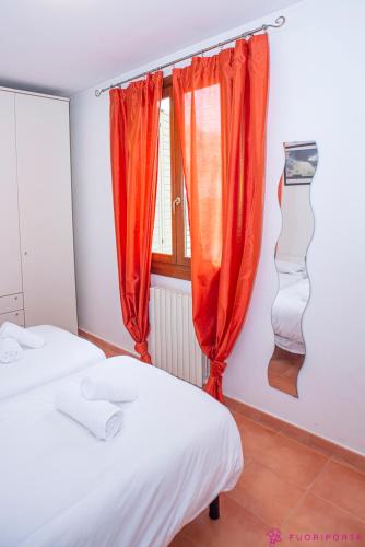 two beds in a room with red curtains and a window at Casa da Luna in Parma