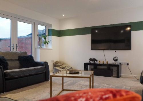 a living room with a couch and a tv on the wall at Fort House Large 6BR Home Sleeps 12 3 Bathrooms NEC, JLR, BHX Nearby in Birmingham