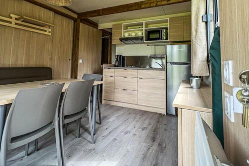 a kitchen with a table and chairs in a trailer at Camping Onlycamp Au Cœur du Lac - Lac d'Annecy in Sévrier