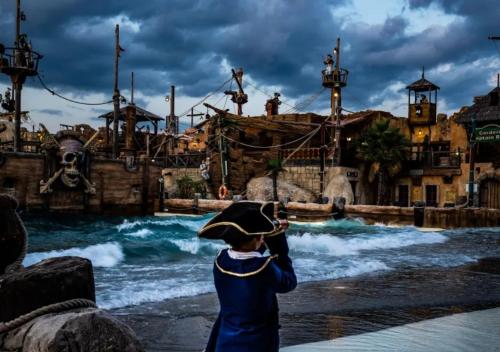 a young boy in a uniform looking at a water park at Camping Les Sables d'Or Pirates World - Aquatique Vacances in Le Grau-dʼAgde