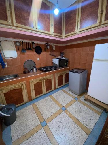 a kitchen with wooden cabinets and a white refrigerator at GUESTS Of TATA in Tatta