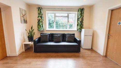 a black couch in a living room with a window at Apple Garden B-4 in London