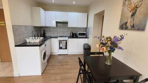 a kitchen with a table with a vase of flowers at Apple Garden B-4 in London