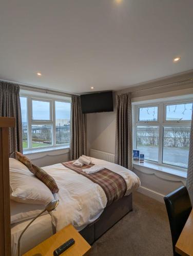 a bedroom with a bed with windows and a desk at King Alfred Hotel in Barrow in Furness