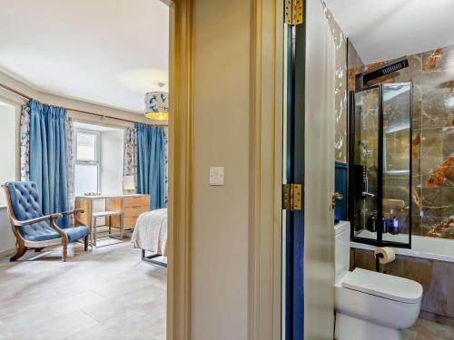 a bathroom with a toilet and a chair and a table at 4 Bed in Newquay oc-90069 in Newquay