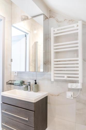 a white bathroom with a sink and a mirror at proche lac et centre parking gratuit in Thonon-les-Bains