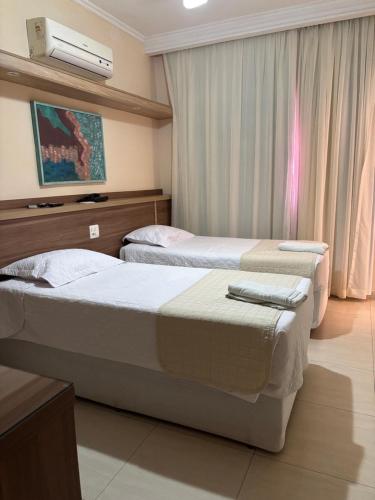 a hotel room with two beds and a tv at Prince Hotel in Ribeirão Preto