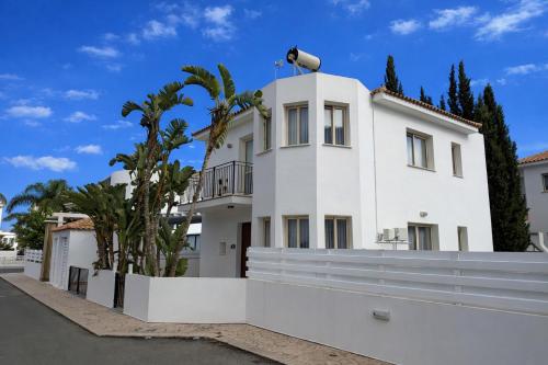 a white house with a fence and palm trees at Villa Dolce Vita in Protaras