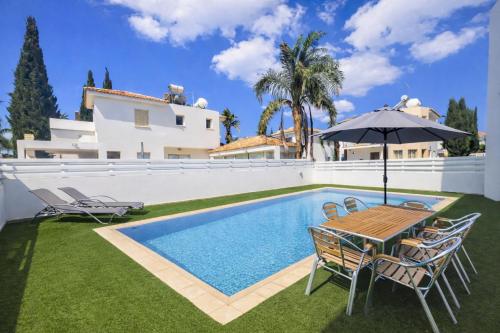 a house with a swimming pool and a table with an umbrella at Villa Dolce Vita in Protaras