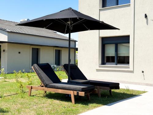two chairs and an umbrella next to a house at Ammos Luxury Pool Villas in Olympic Beach