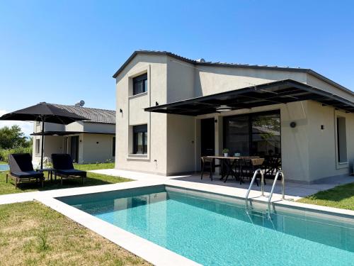 a house with a swimming pool in front of a house at Ammos Luxury Pool Villas in Olympic Beach