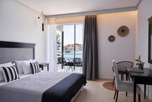 a bedroom with a bed and a desk and a balcony at Xenia Poros Image Hotel by GHH in Poros