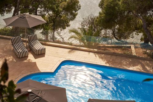 a swimming pool with two chairs and an umbrella at Xenia Poros Image Hotel by GHH in Poros