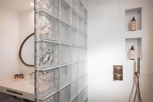 a bathroom with a wall of glass shelves at Hôtel Briketenia in Guéthary