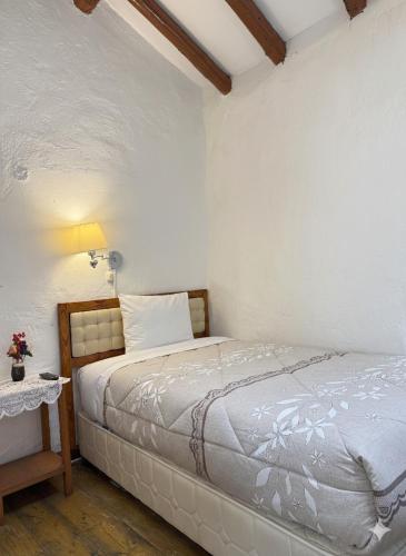 a white bedroom with a bed and a table at Naty's Guest House in Cusco