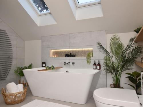a bathroom with a white tub and a toilet at 4 Bed in Bude oc-83619 in Stratton