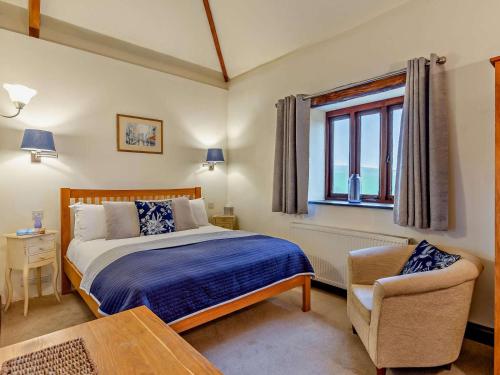 a bedroom with a bed and a chair and a window at 4 Bed in Boscastle oc-47035 in Boscastle