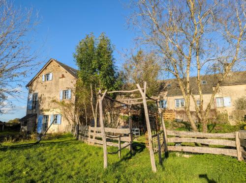 ein altes Haus mit einem Holzzaun im Hof in der Unterkunft Saisonnée - Chambres d'Hôtes et Table d'Hôtes en Aveyron in Centrès